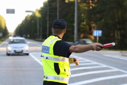 Certified traffic controller in reflective vest directing vehicles on a busy road, ensuring job site safety and smooth traffic flow for Maintenance Man Unlimited