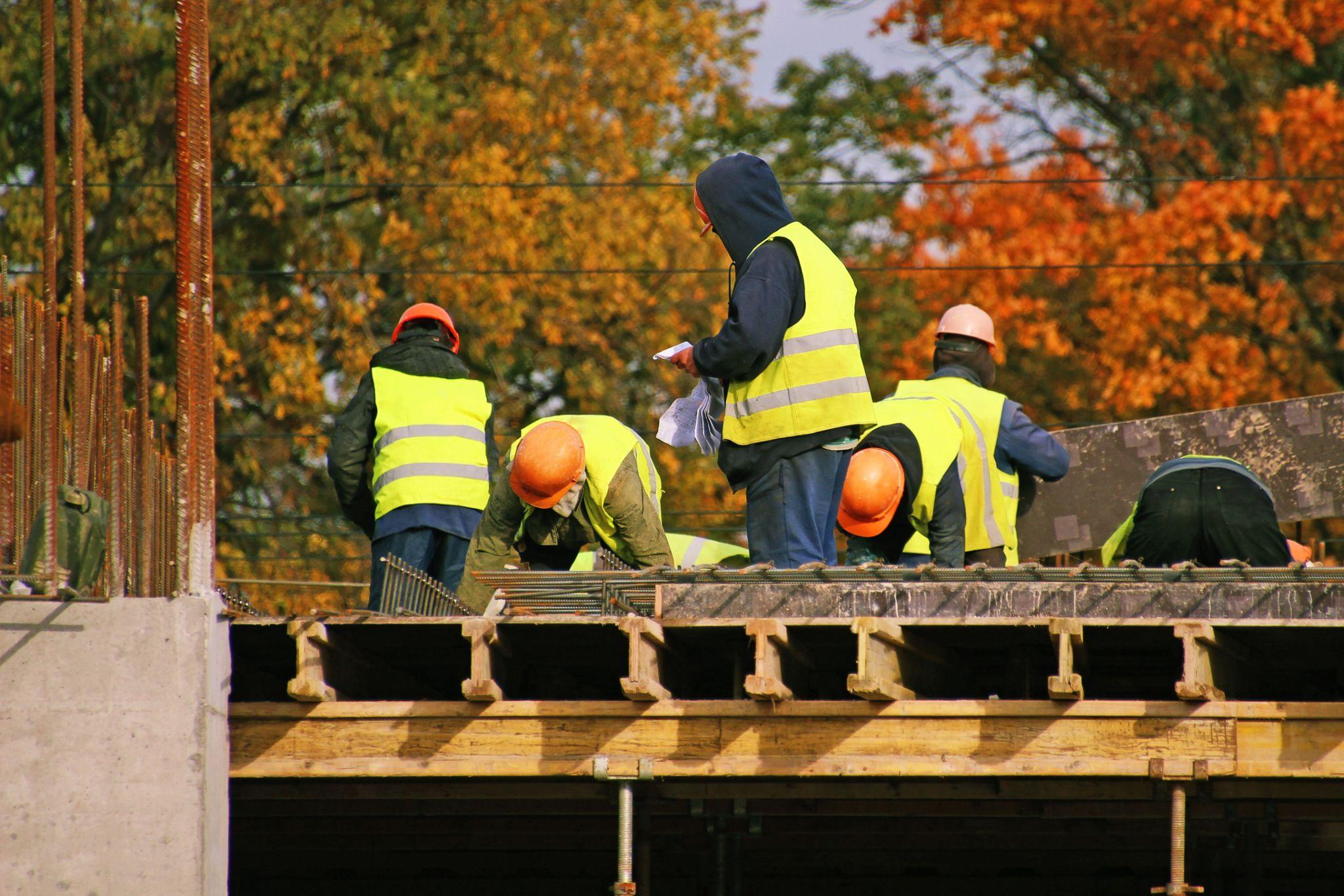 Construction workers in safety vests collaborating on a building project, symbolizing reliable, consistent crews that keep projects on schedule and reduce downtime.
