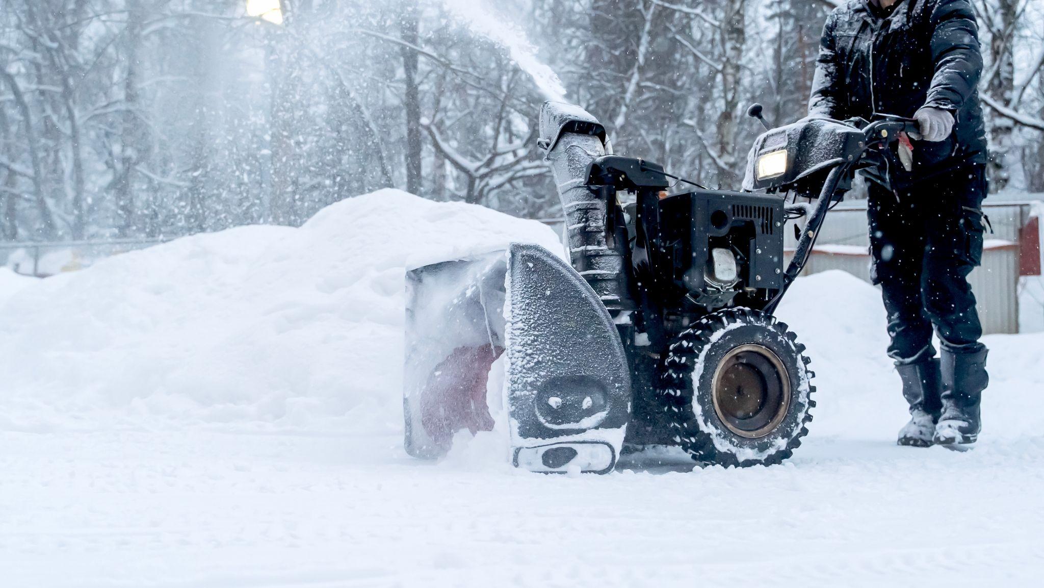 Technician operating a snow blower to clear deep snow from a parking lot, keeping the job site safe, accessible, and winter-ready.