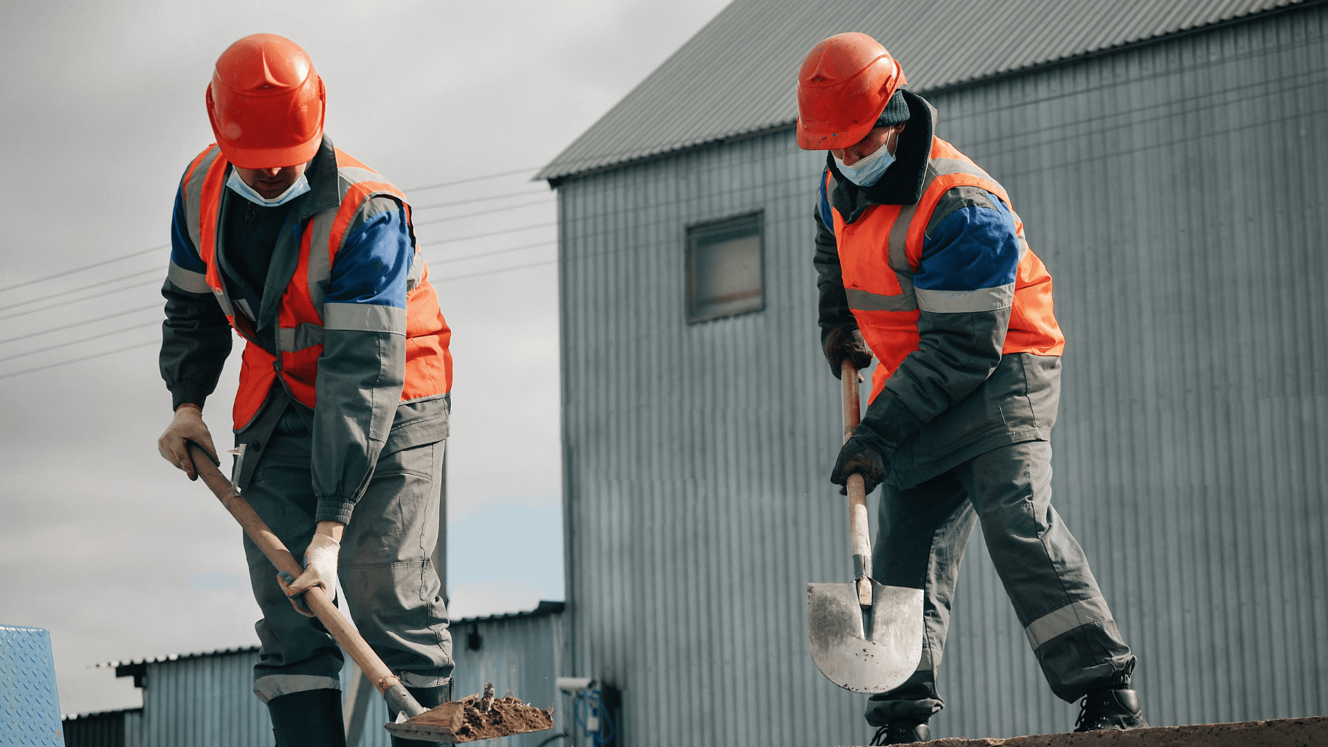 A pair of construction workers digging at dirt