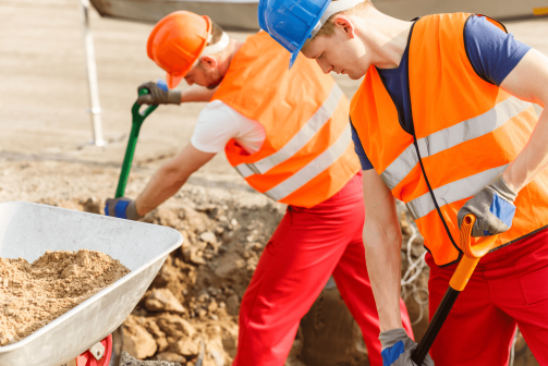 A pair of construction workers shoveling dirt