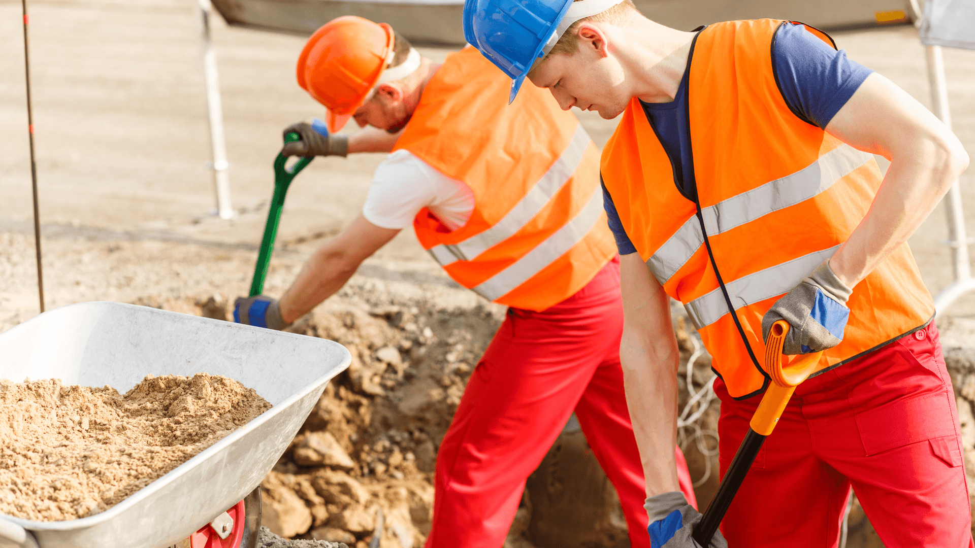 A pair of construction workers shoveling dirt