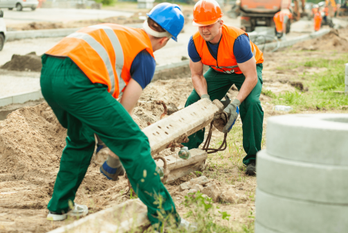 A pair of construction workers lifting concrete