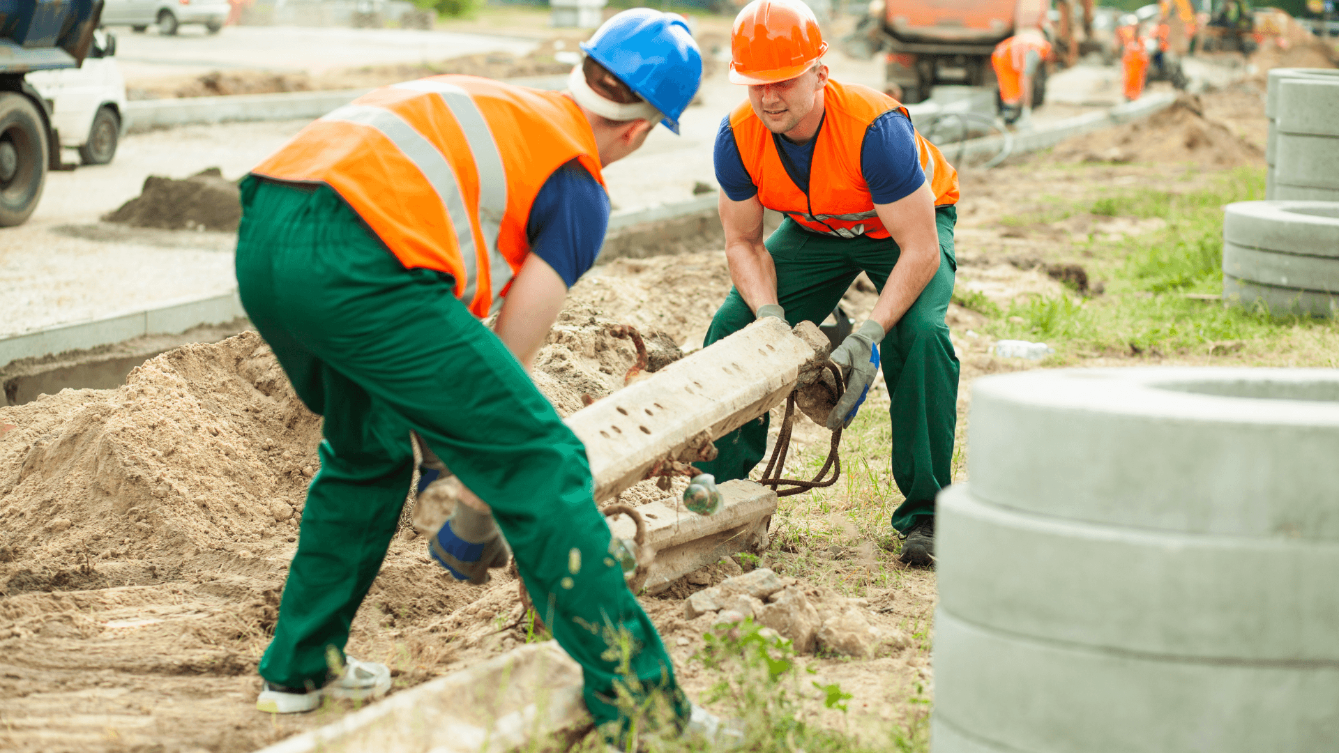 A pair of construction workers lifting concrete