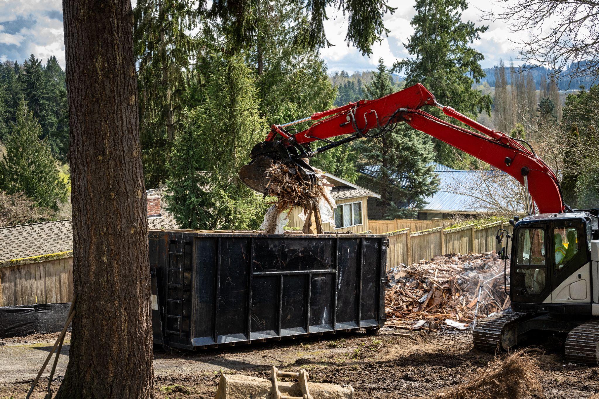 Excavator clearing construction debris into a dumpster at a Seattle-area project site