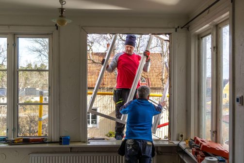 Two workers installing a replacement window during building maintenance