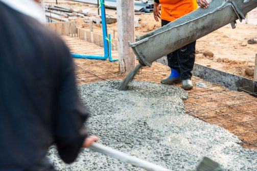 Workers pouring concrete into a reinforced foundation on a construction site