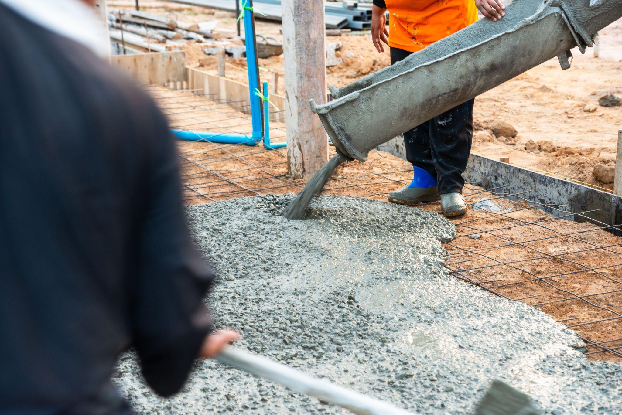 Workers pouring concrete into a reinforced foundation on a construction site