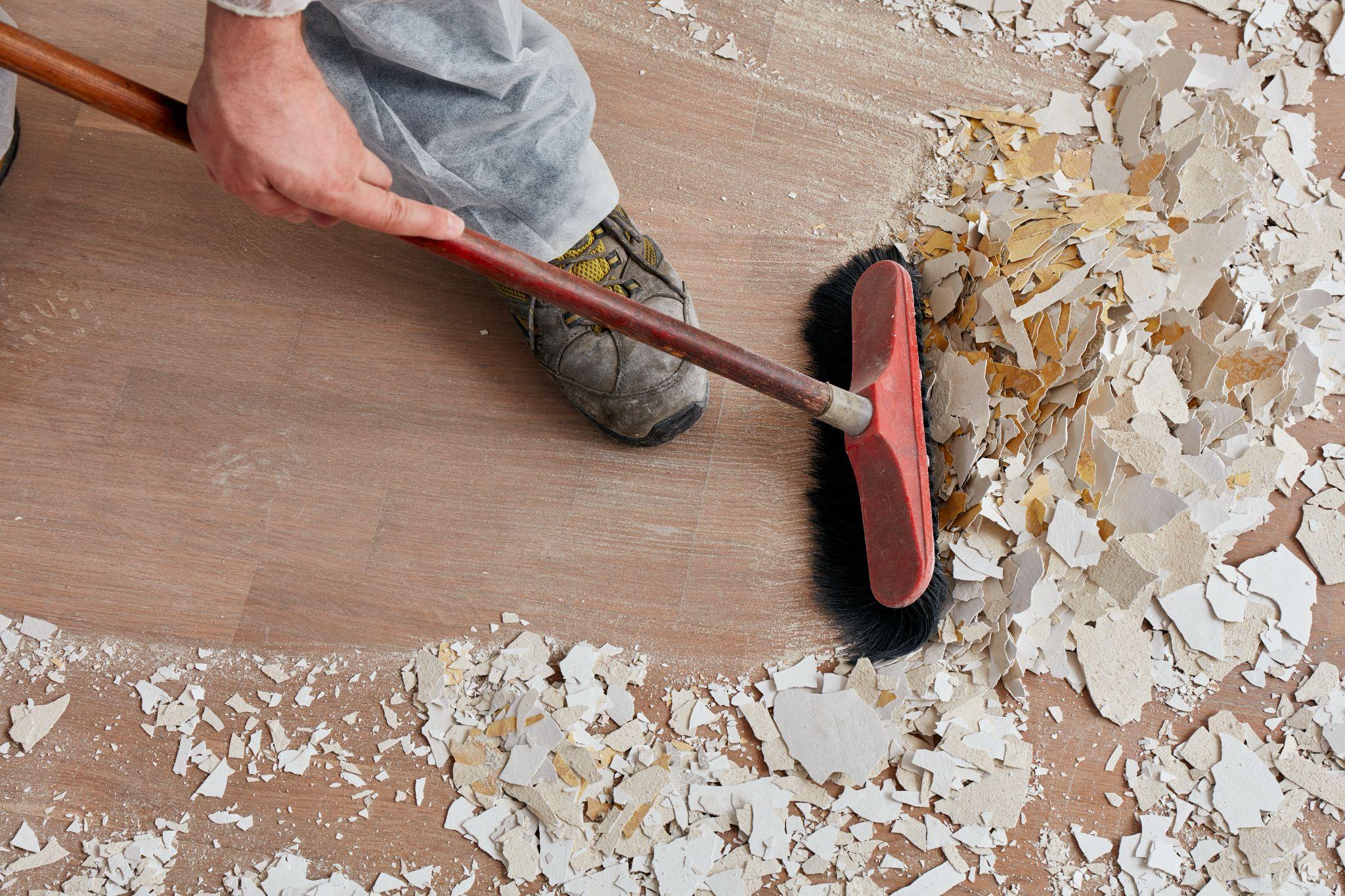 Worker sweeping construction debris off a floor during jobsite cleanup