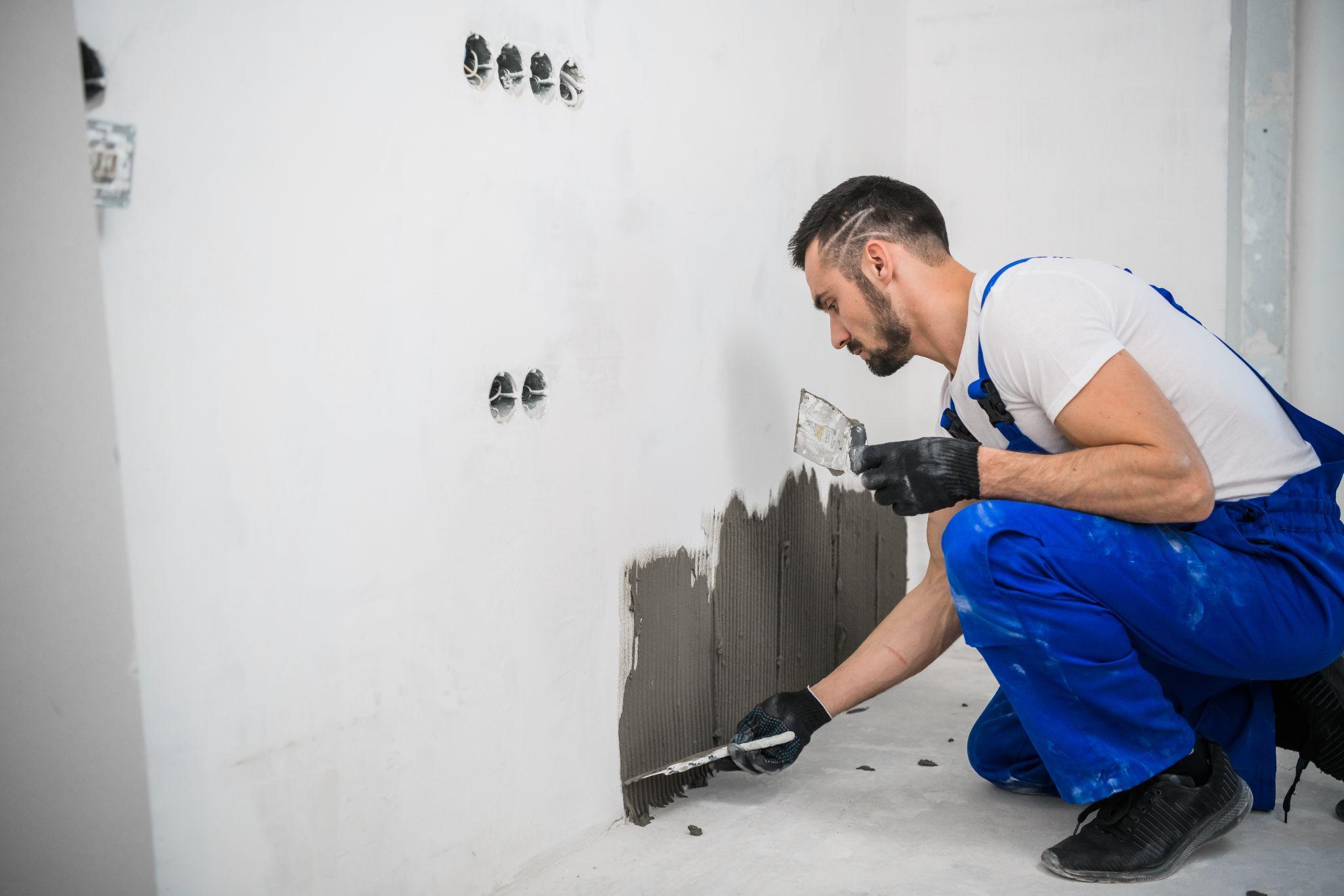 Construction worker applying adhesive to a wall during interior finishing work