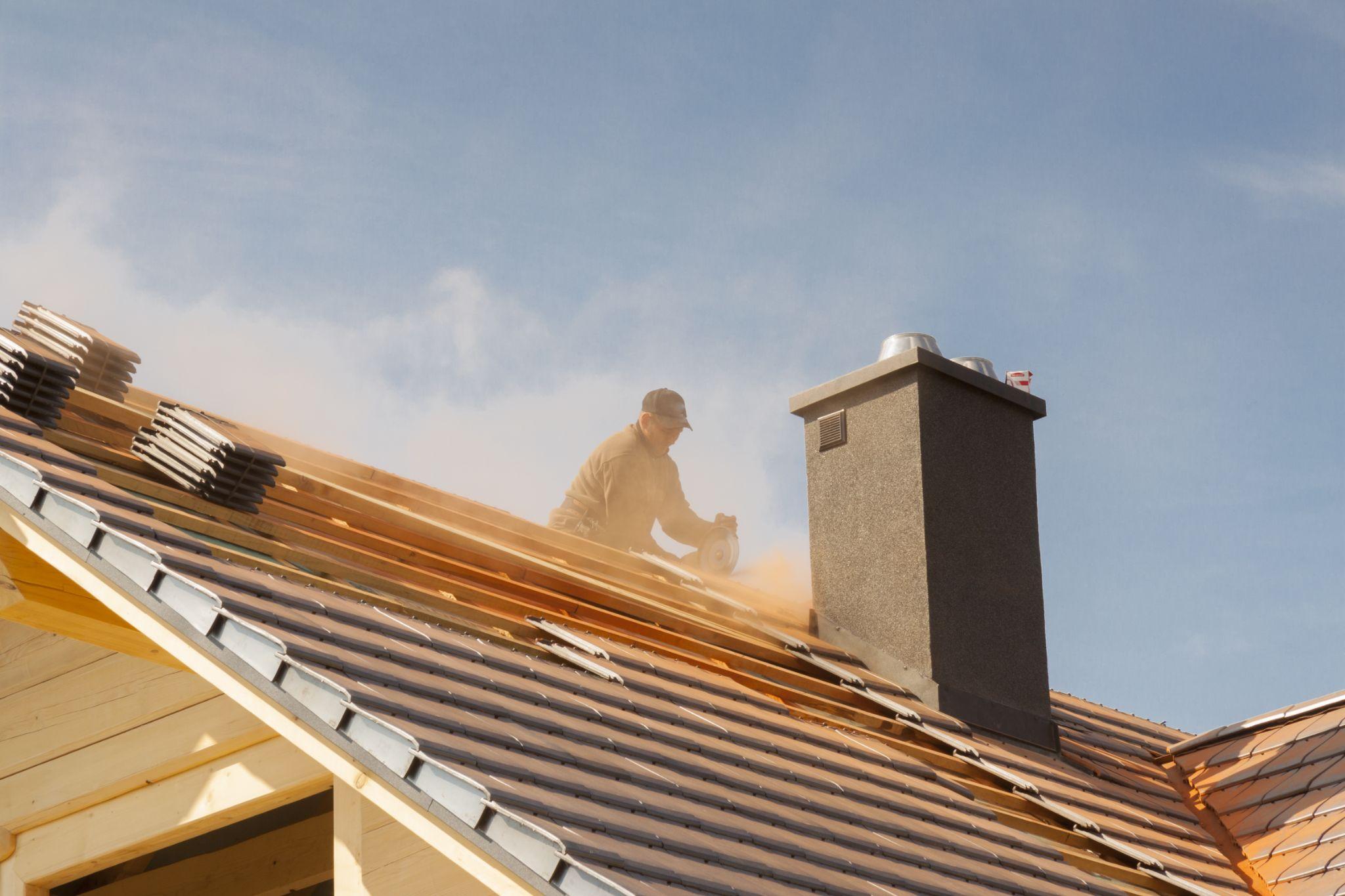 Roofer cutting tiles during the final stages of a construction project